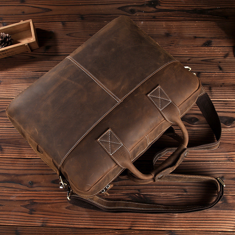 Rustic leather men's shoulder bag with vintage styling on wooden backdrop