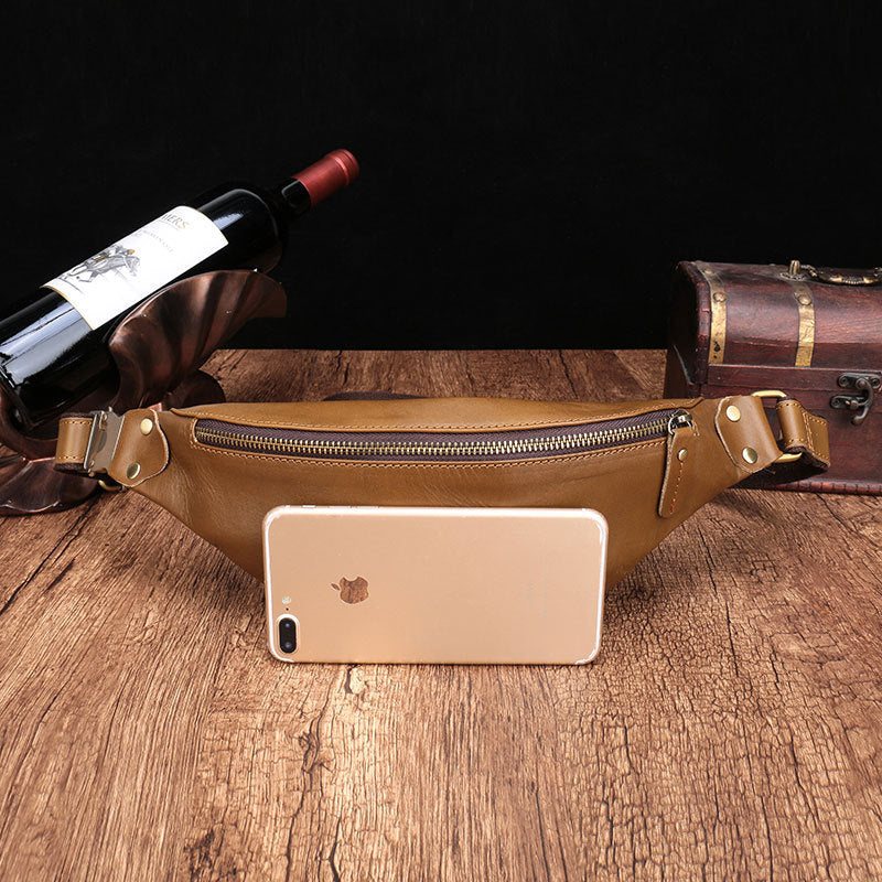 Leather men's brown leather cell phone belt bag on wooden table with wine bottle and vintage suitcase