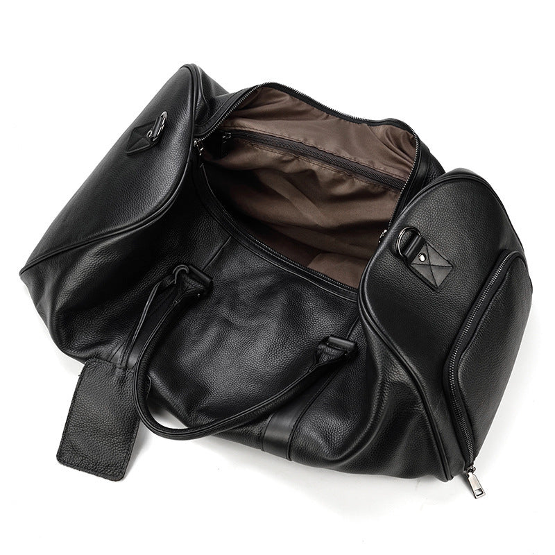 Large black leather business travel bag with multiple compartments and zipper details, suitable for carrying various essentials during business trips or daily commute.