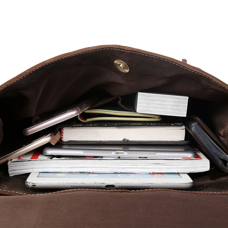 Vintage men's backpack with multiple compartments and pockets, filled with various office and electronic items such as documents, tablets, and notebooks.