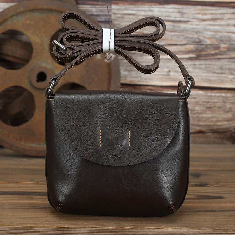 Retro simple leather crossbody bag with braided strap for women, featured on wooden background.