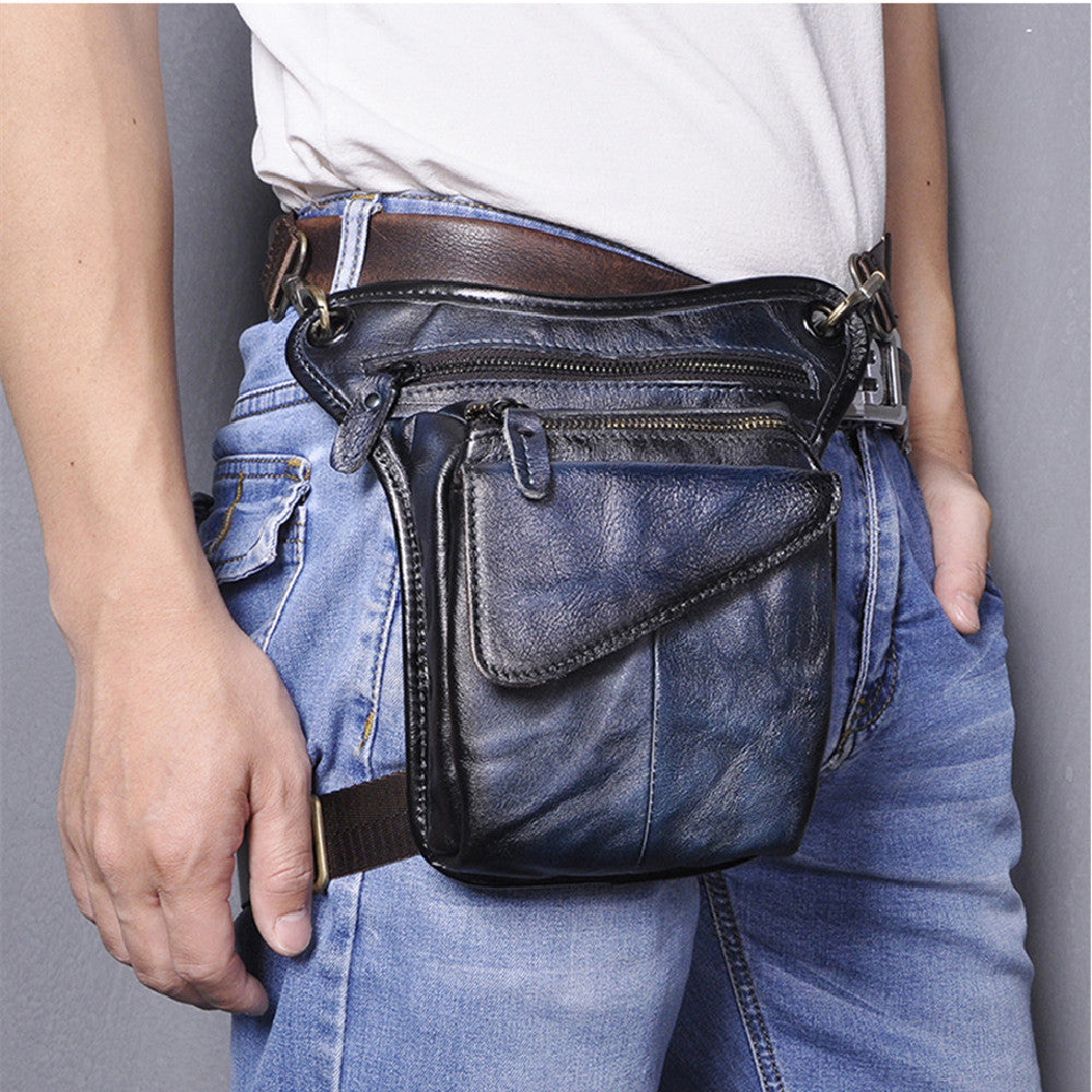 Stylish black leather waist bag with multiple zippers and pockets, worn by a person with casual denim outfit.