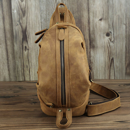 Rugged Leather Chest Bag - Durable tan-colored leather chest bag with zipped main compartment and adjustable shoulder strap, designed for style and functionality.