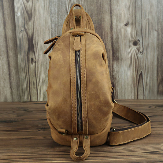 Rugged Leather Chest Bag - Durable tan-colored leather chest bag with zipped main compartment and adjustable shoulder strap, designed for style and functionality.