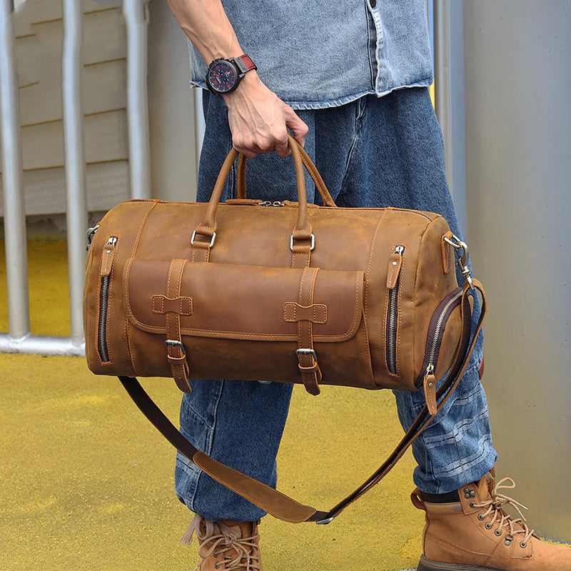 Large Leather Travel Bag with Multiple Pockets and Straps, Held by Man in Casual Outfit