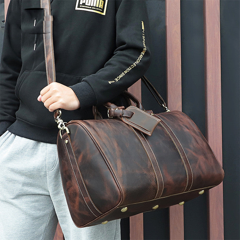 Vintage Distressed Leather Travel Luggage Bag held by a person wearing a black Puma brand sweatshirt